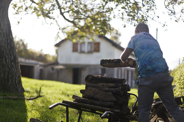 Damien, le fils de Carole, s'occupe de faire le bois, dans le jardin.